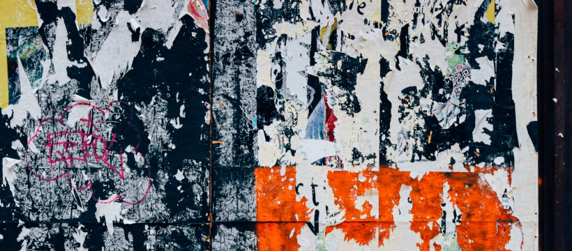 Gros plan sur un ensemble d’affiches collées sur un mur, motifs abstraits en noir blanc et rouge.