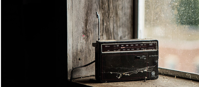 Vieux poste de radio posé sur un cadre de fenêtre en bois, en contre-jour.