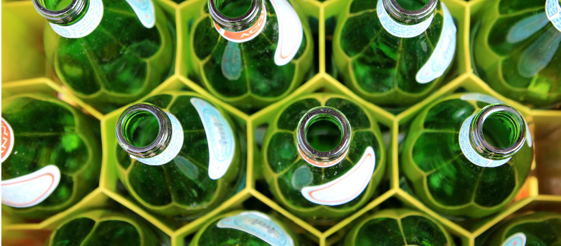 Bouteilles de bière vertes rangées dans un casier, vues du dessus.
